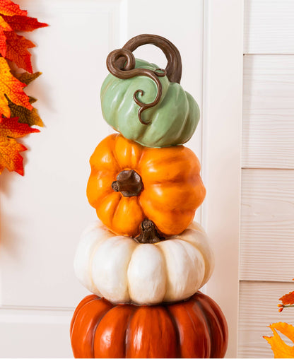 Stack of orange, white, and turquoise pumpkins on an urn for front porch