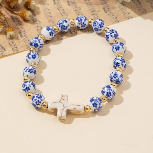 blue and white toile patterned beaded bracelet with a creamy gold cross.