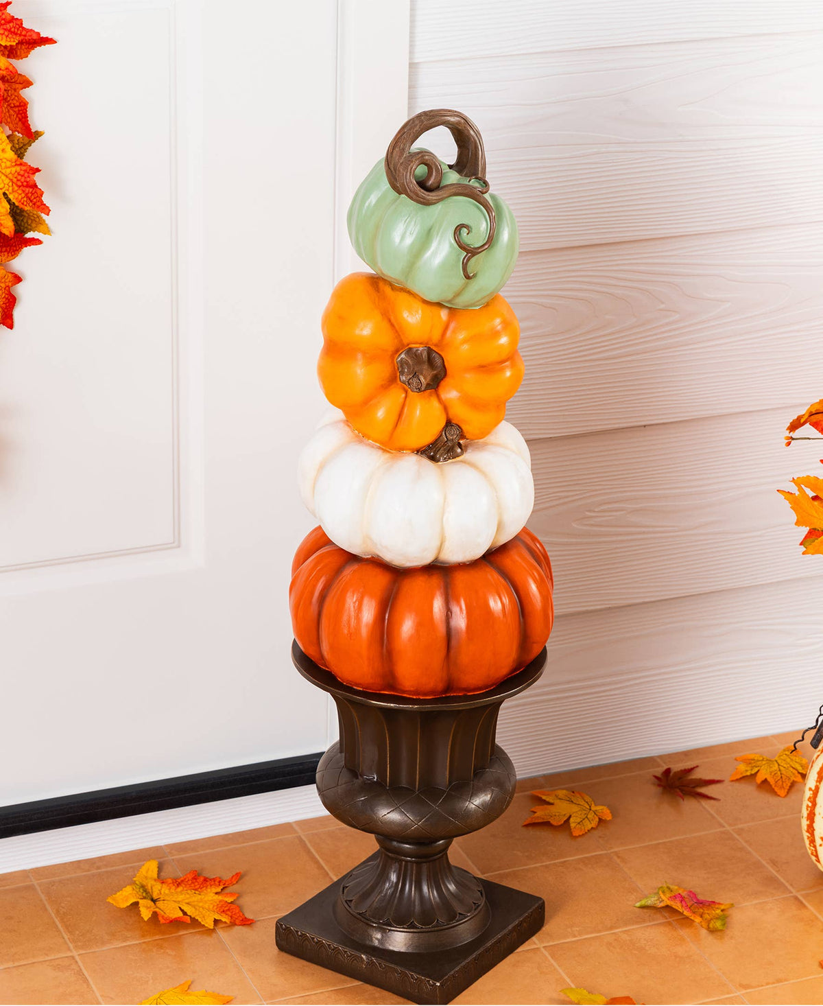 Stack of orange, white, and turquoise pumpkins on an urn for front porch