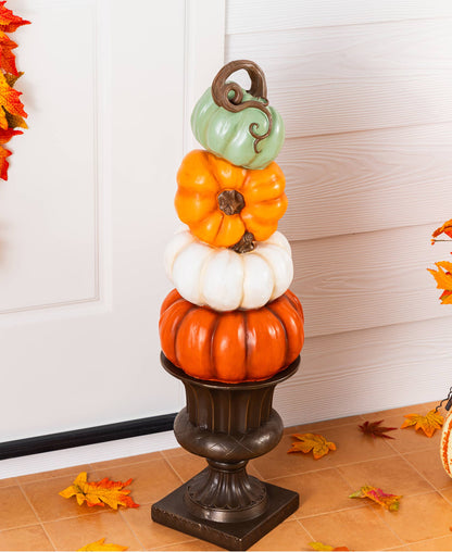 Stack of orange, white, and turquoise pumpkins on an urn for front porch