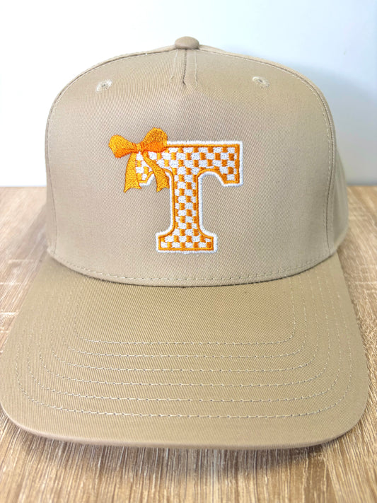 Tan hat with orange and white checkered T with orange bow 