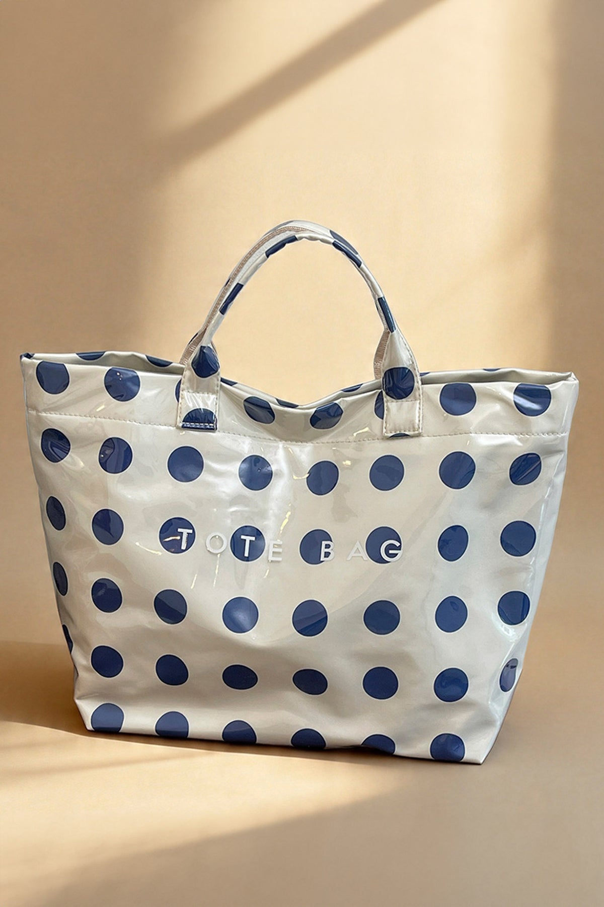 Glossy Waterproof gray tote bag with blue polka dots with the word "tote bag" across the front