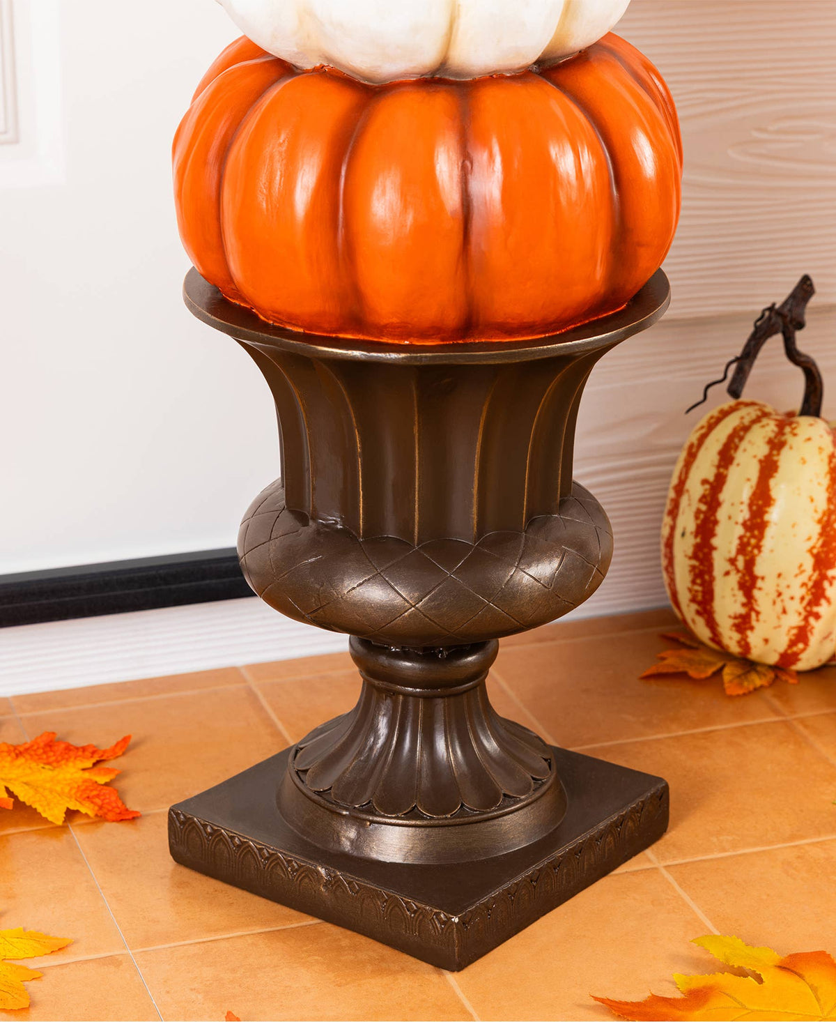 Stack of orange, white, and turquoise pumpkins on an urn for front porch